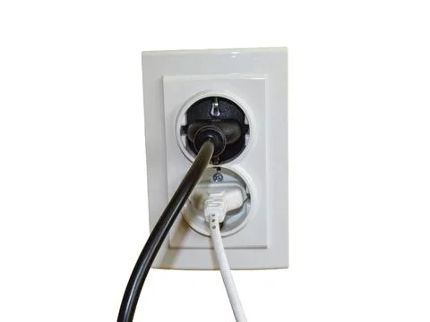 A black plug and a white plug in the socket Foto stock