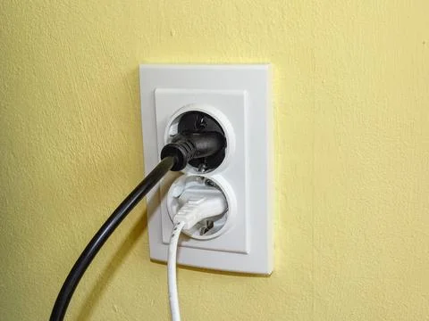 A black plug and a white plug in the socket Foto stock