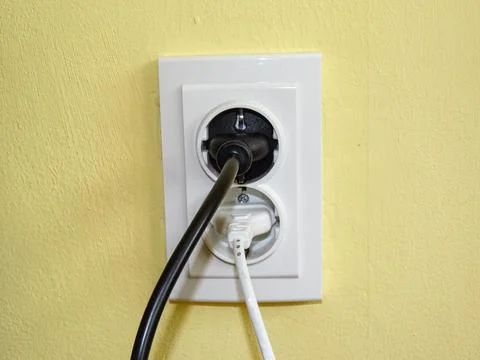 A black plug and a white plug in the socket Stockfoto's