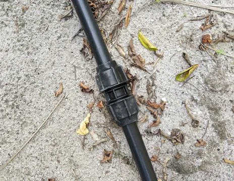 The black poly pipe that is on the ground after being repaired. Stock Photos