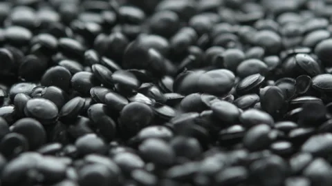 Black polyethylene pellets fall from above onto granules layer in macro, Stock Footage 334659502