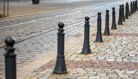 Black posts separating paved street and path Stock Photos