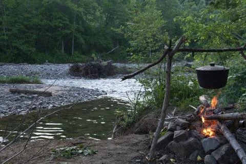 Black pot on a background of trees and river. Stock Photos