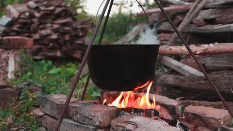 Black pot with food hanging over the fire close-up, cooking soup outdoors Stock Footage 159878053