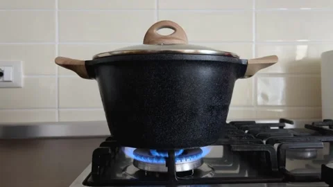Black pot with lid on flame of kitchen gas stove Stock Footage 267485154