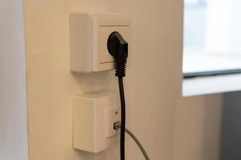 Black Power Plug Connected to Wall Outlet with Data Socket 库存照片