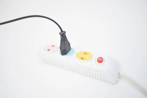 A black power plug inserted into a colorful multi-socket extension cord on .. Stock Photos
