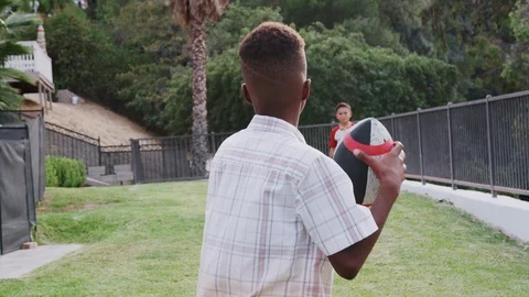 Black pre-teen boy throwing a football t... | Stock Video