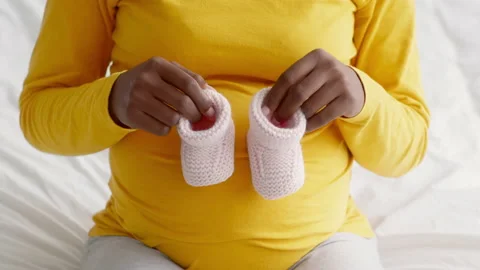 Black Pregnant Lady Playing With Tiny Baby Shoes, Stepping On Her Belly Stock Footage 163805165