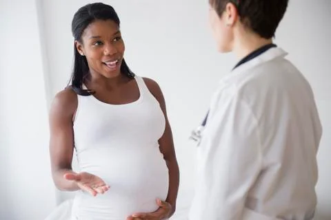 Black pregnant woman talking to doctor Stock Photos