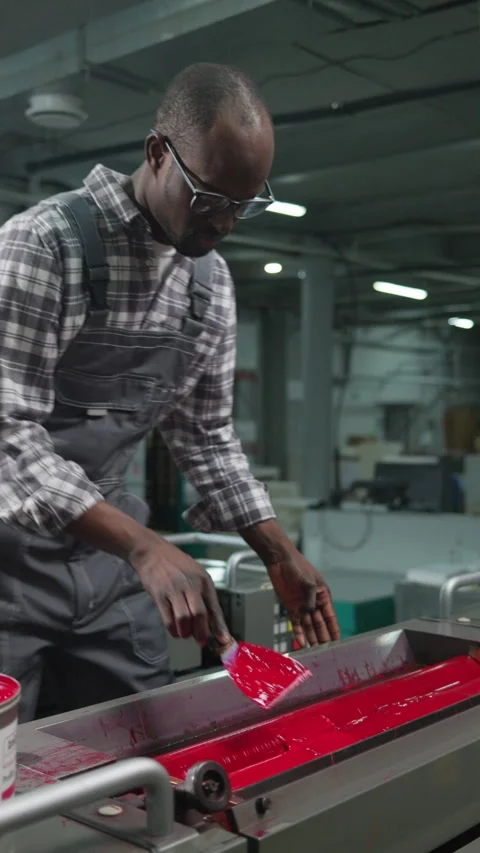 Black Printing Factory Technician Applying Red Ink to Press Roller Video stock 335482459