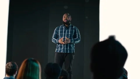 Black product manager introducing new mobile phone product at conference hall Stock Footage 327624461