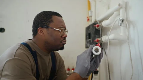 Black Professional Plumber Examining Pipe Valve for Installation Stock Footage 340614700