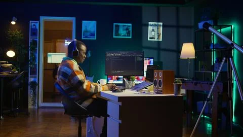 Black programmer remotely working in home office writing code on computer Stockfoto's