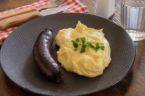 Black pudding cooked with mashed potatoes in a plate on a table Stock Photos