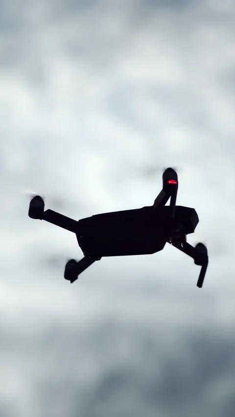 Black quadcopter drone silhouette flying against an overcast cloudy sky Stock Footage 344891146