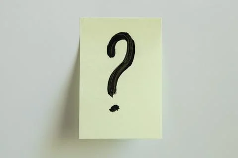 A black question mark painted on a yellow sticky note placed on a white Stock Photos