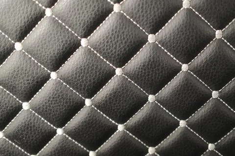 Black quilted leather surface with white diamond stitching Stock Photos