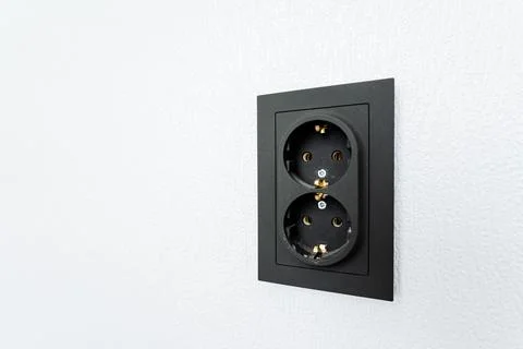 A black rectangular electrical outlet mounted on a white wall Stock Photos