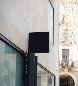 Black rectangular mockup signboard hanging on classic building wall Foto stock