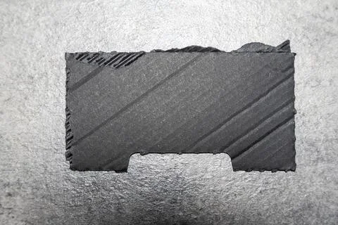 A black rectangular piece of textured paper placed on a gray background. This Stock Photos