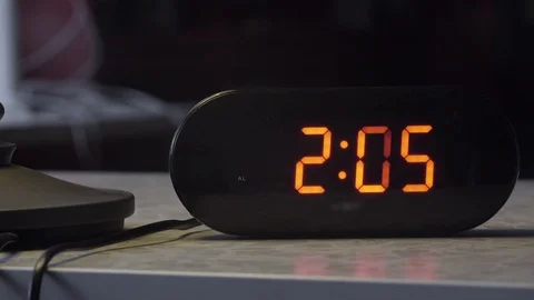 Black rectangular shaped plastic digital clock indicates time in orange color Stock Footage 100784869