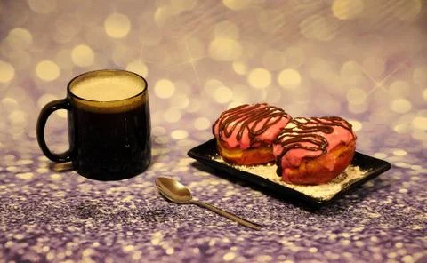 A black rectangular tarekla with two donuts in pink glaze, with chocolate spr Stock Photos
