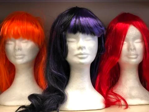 Black, red and orange long wigs on female mannequins. Halloween, carnival Foto stock