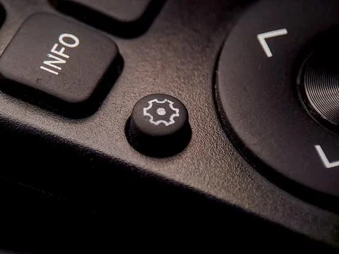 Black remote control button with a white gear icon to access settings and a.. Stock Photos