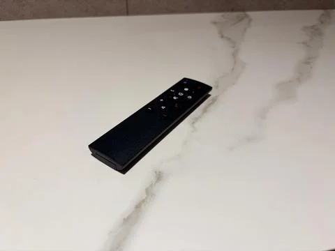 Black remote control on a white marble surface. Stock-Fotos