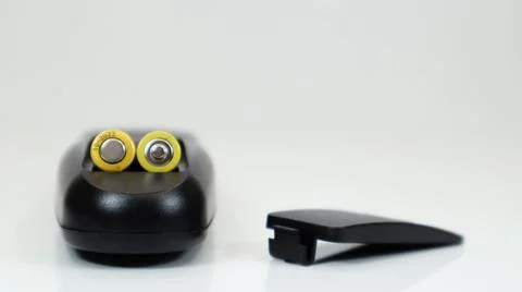 Black remote control with yellow AAA batteries on a white background. Batte.. Stockfoto's