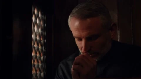 The black-robed priest folded his hands in prayer. The gray-haired pastor Stock Footage 234897482