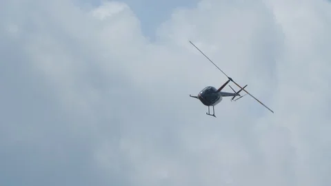 Black robinson helicopter makes loop and maneuver diagonally and fly through sky Video stock 120582002