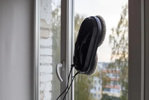 Black robot window cleaner washes a window in city apartment. the cleaning .. Stock Photos