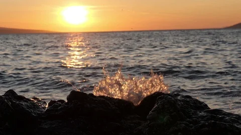 Black rocks and splashes of wave blinking in sunset light. Sea shore Stockbeeldmateriaal 125641005