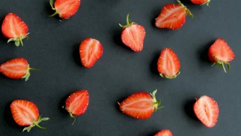 Black rotating background with strawberry halves, close up Stock Footage 132311299