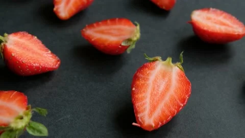 Black rotating background with strawberry halves, close up Stock Footage 132311305