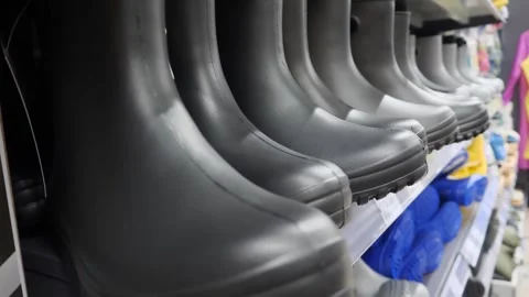 Black rubber boots, standing in a row on a store shelf. Stock Footage 302293546