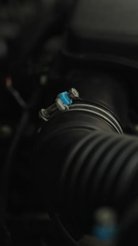 A black rubber engine air duct pipe secured with a metal clamp with a blue Stock Footage 336710246