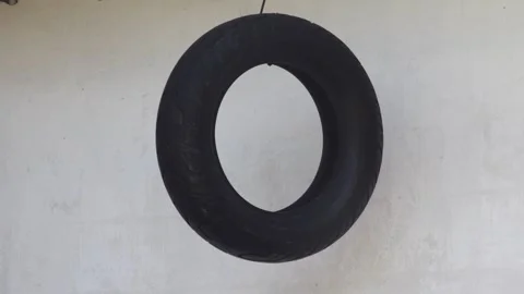 Black rubber motorcycle tire hanging against a plain white wall in an auto .. Stock Footage 344819004