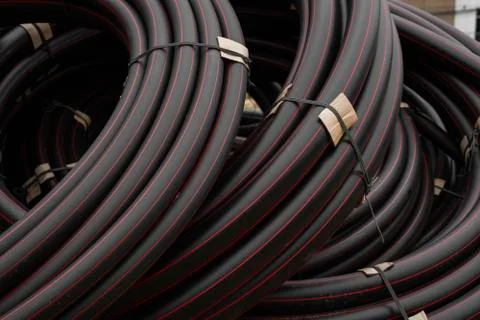 Black rubber or plastic pipes with a red lines as a construction material and Stock Photos