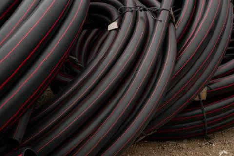 Black rubber or plastic pipes with a red lines as a construction material and Stock Photos