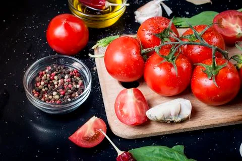Black rustic tabletop with branch of tomatoes and herbs, top view Photos