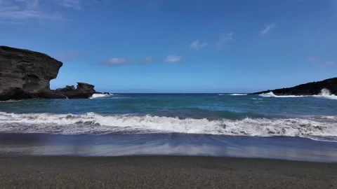 Black sand beach with rolling waves in Hawaii Stockbeeldmateriaal 347826314