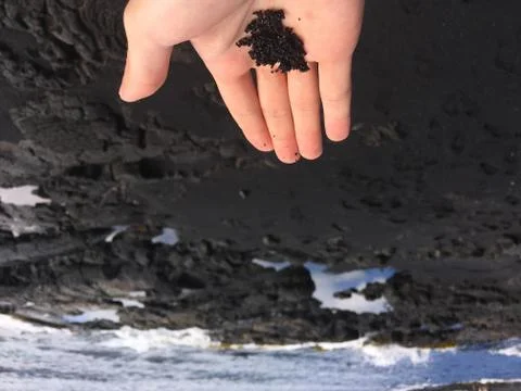 Black sand held in hand Stock Photos
