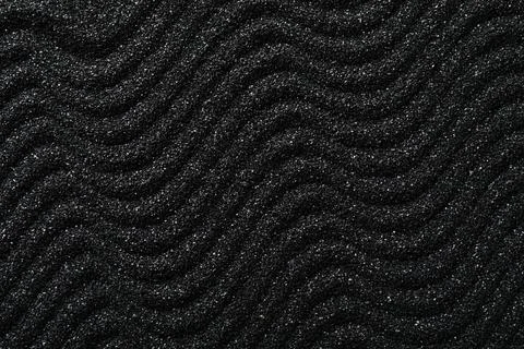 Black sand texture with wavy patterns, dark granular surface background, mini Stock Photos