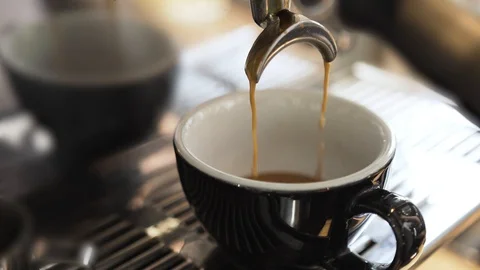 Black saturated coffee is poured into a cup from a coffee machine in coffee shop Stock Footage 129262132