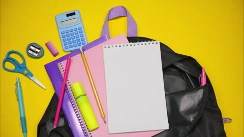 Black school backpack full of school supplies on yellow background. Stop motion Stock Footage 284631838