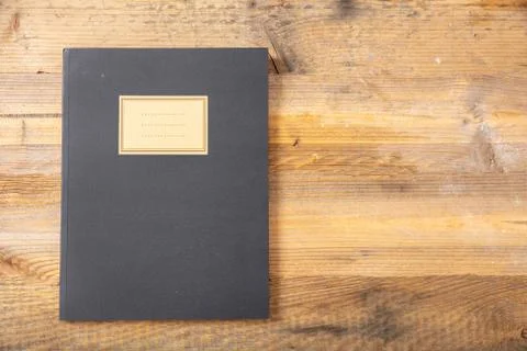 Black school notebook or diary, old fashioned, isolated on wooden background, Foto stock