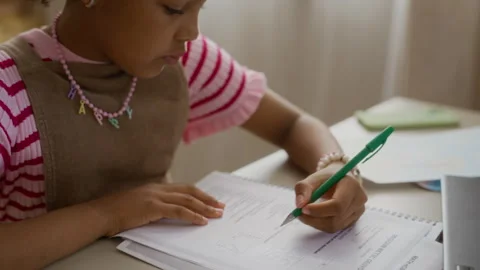 Black Schoolgirl Writing in Notebook, Doing Math Homework Stock Footage 337570788